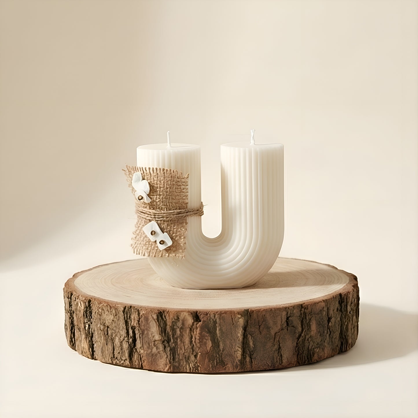 Curved white luxury candle with textured surface, burlap accent, on wooden slab