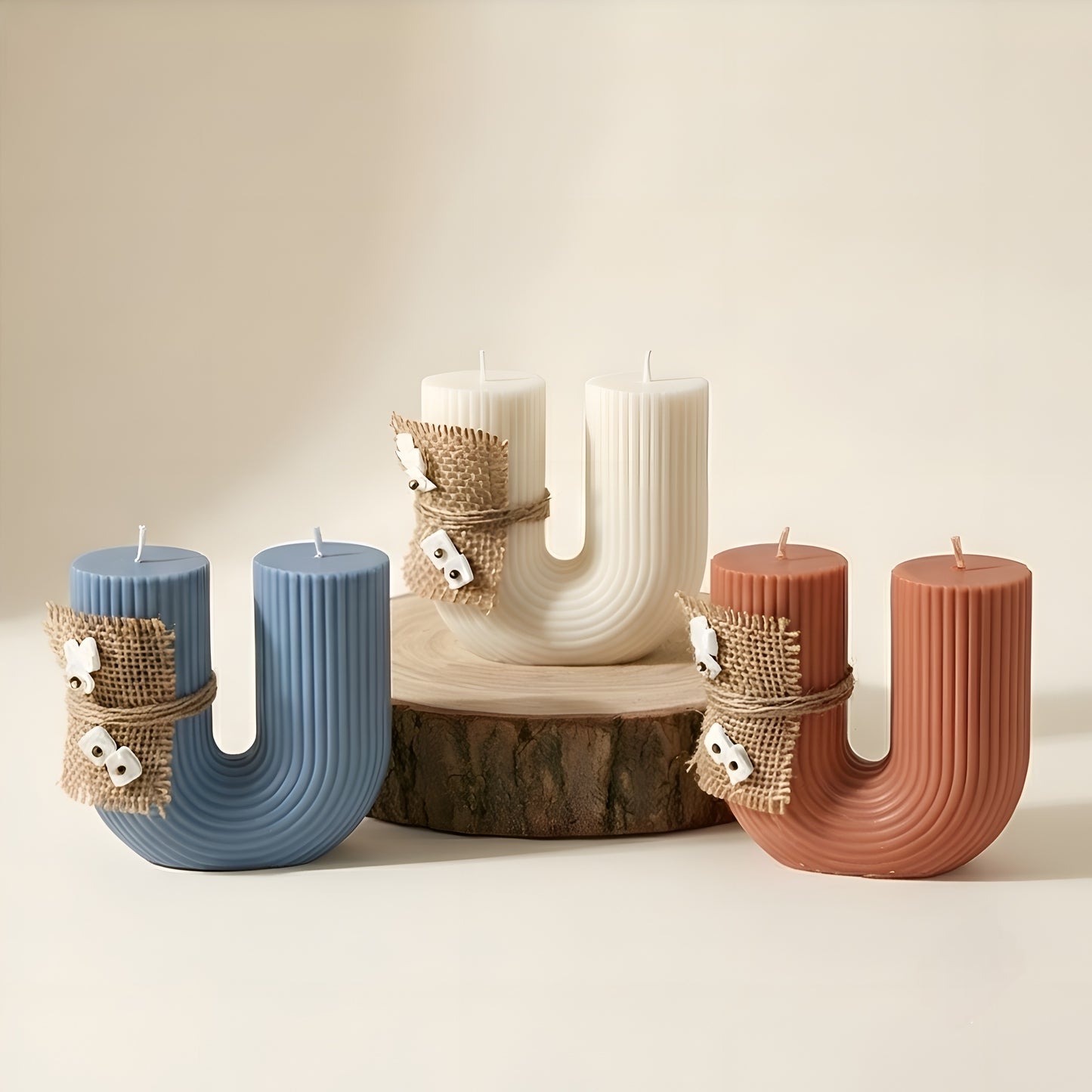 Set of ribbed U-shaped luxury candles in blue, white, and terracotta on wooden stand